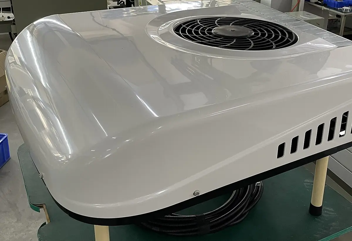 White rooftop RV air conditioner shroud with the fan grille showing, sitting on a workbench