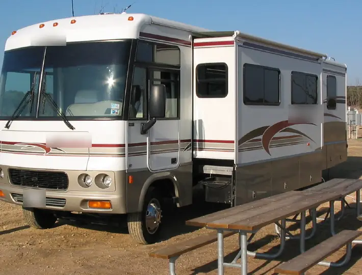 Class A motorhome at a campsite with its side slide-out room extended